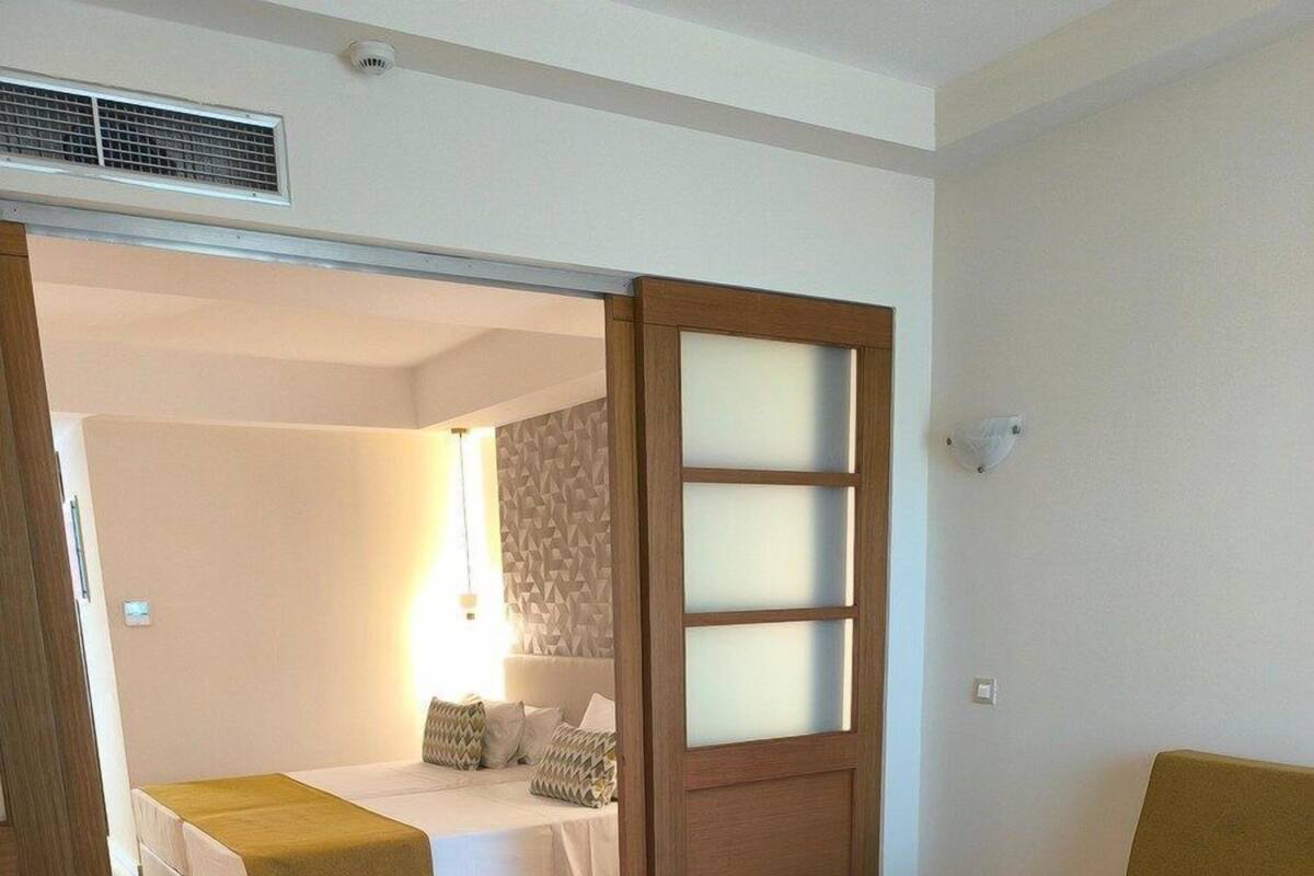Une pièce comprenant un lit, un canapé et une porte coulissante donnant sur une autre pièce.