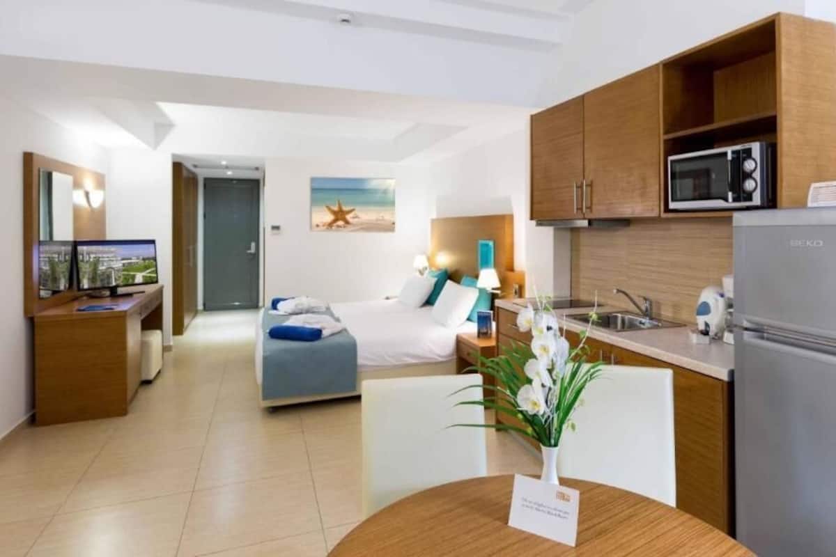 Une chambre d’hôtel moderne équipée d’un lit, d’une petite kitchenette, d’un coin repas et d’une salle de bain.