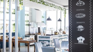A modern dining area with a white and blue color scheme, featuring a central island with a kitchen in the background. - Asterias Beach Resort (Rhodes)