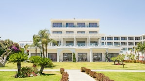 A multi-story hotel with a central courtyard, outdoor seating, and a well-maintained garden. - Asterias Beach Resort (Rhodes)