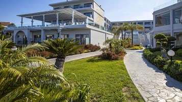 A modern hotel with a rooftop terrace, lush landscaping, and a stone pathway.