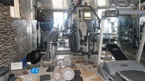 A gym with various exercise equipment, including a treadmill, weight machines, and dumbbells. - Charlie's Place And Suite (Lagos)