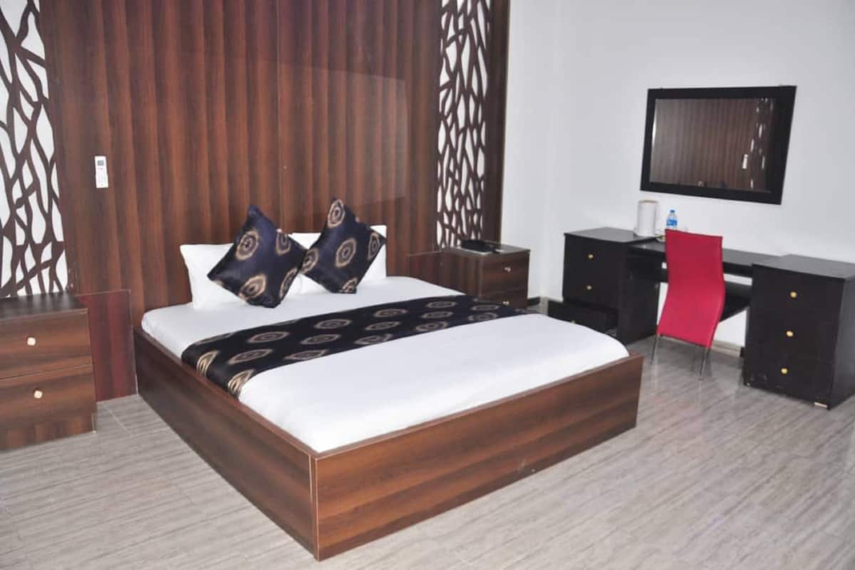 A modern bedroom with a wooden bed, two nightstands, a desk, and a red chair.