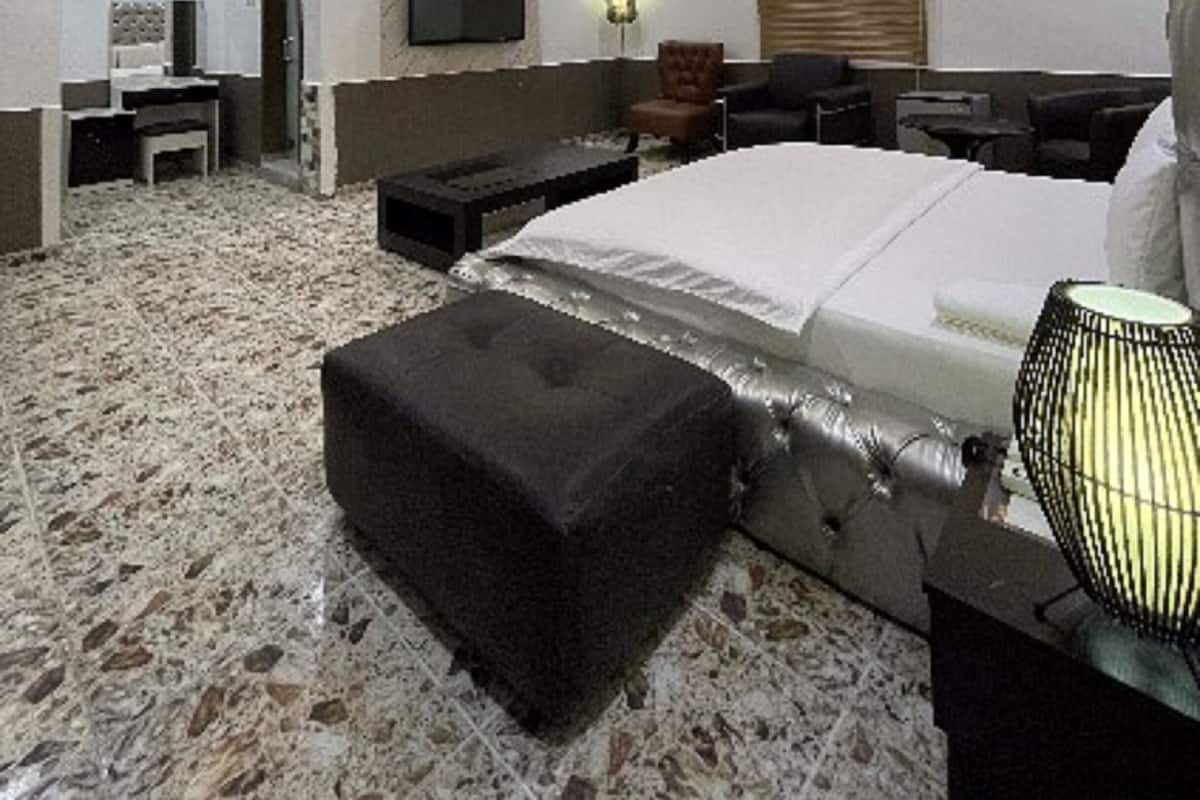 A modern bedroom with a large bed, a desk, and a TV.