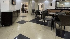 A modern dining area with a chandelier, a large mirror, and a black and white checkered floor. - Charlie's Place And Suite (Lagos)