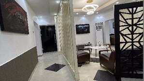 A modern interior with a tiled floor, a staircase, a dining area with chairs and a table, and a decorative partition. - Charlie's Place And Suite (Lagos)