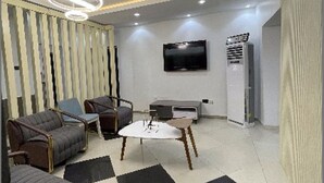 A modern living room with sofas, a coffee table, a TV, and a built-in air conditioner. - Charlie's Place And Suite (Lagos)