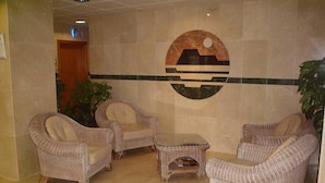 A lobby with wicker furniture, a tiled floor, and a wall-mounted logo.