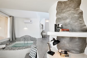 Een moderne woonkamer met een stenen muur, een zwembadje, een bank en een bureau met boeken.
