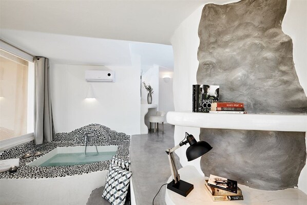 A modern living room with a stone wall, a small pool, a sofa, and a desk with books.