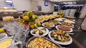 Un bufé con diversas opciones de comida, incluyendo frutas, postres y bebidas.