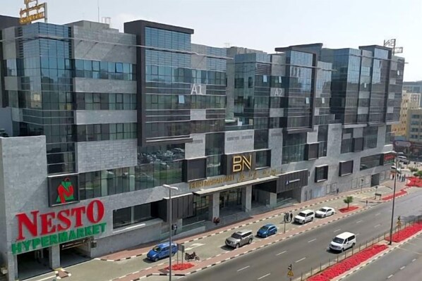 A modern building with a large sign for NESTO Hypermarket. - Fortune Hotel Deira (Dubai)
