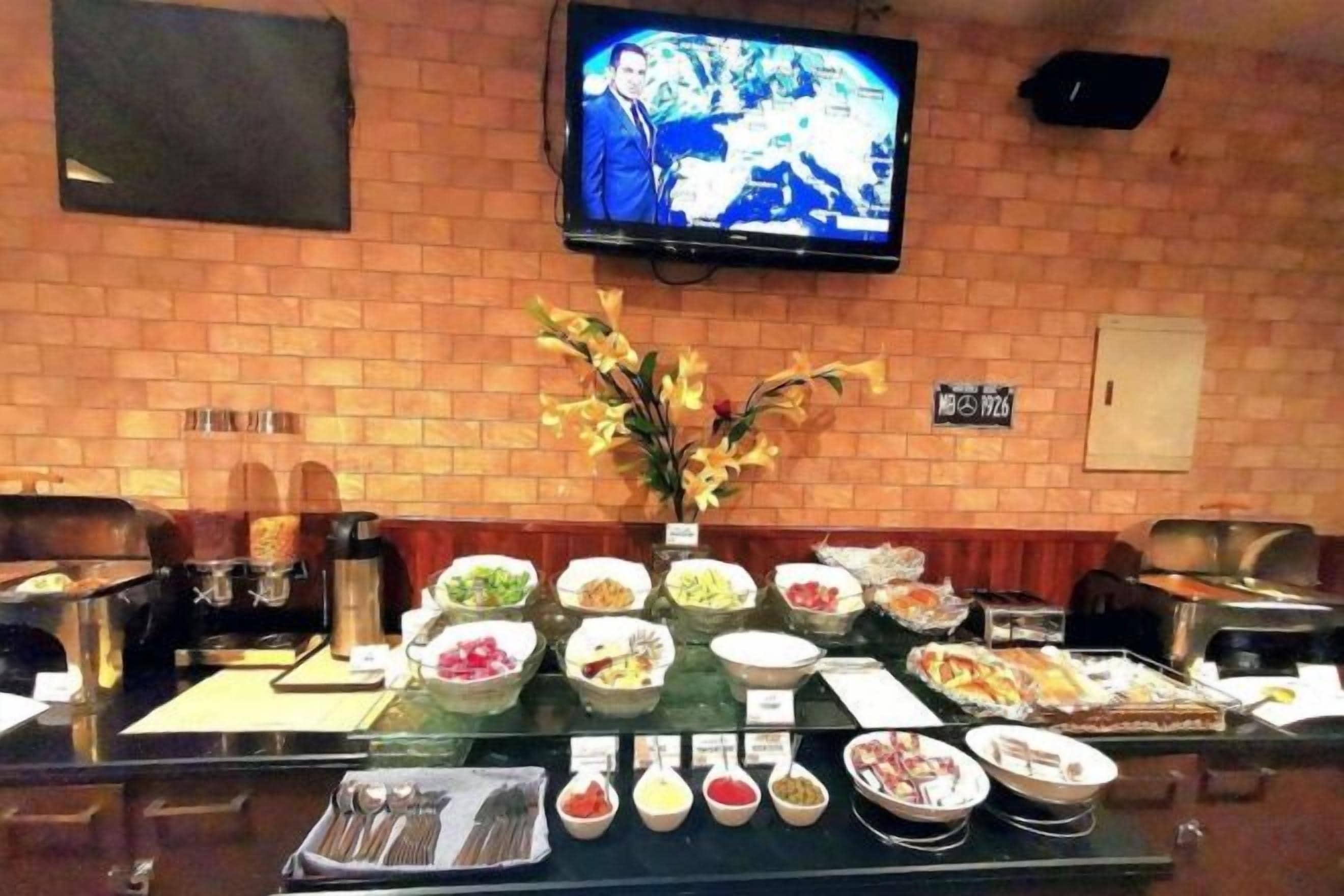 A buffet setup with various food items and a television mounted on the wall.