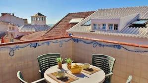 A rooftop terrace with a table set for two, two chairs, a yellow teapot, and two cups on a tiled table. - Villa Ana Margarida Residences (Mafra)