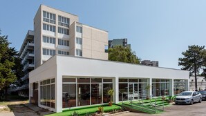Un edificio moderno con techo plano, ventanas amplias y un césped.