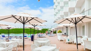 A rooftop terrace with white tables and chairs, large umbrellas, and a pool in the background. - Mh Peniche, Peniche, Portugal (Peniche)