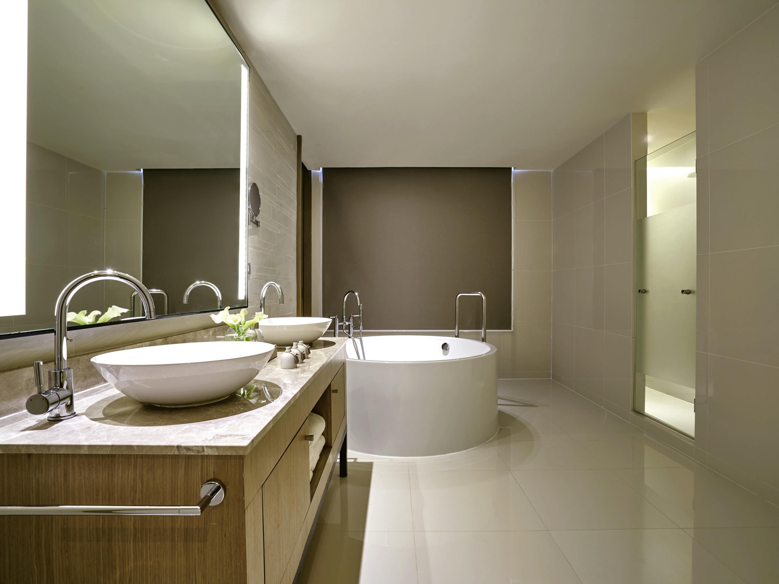 Une salle de bain moderne avec un double vasque, une grande baignoire et un miroir.