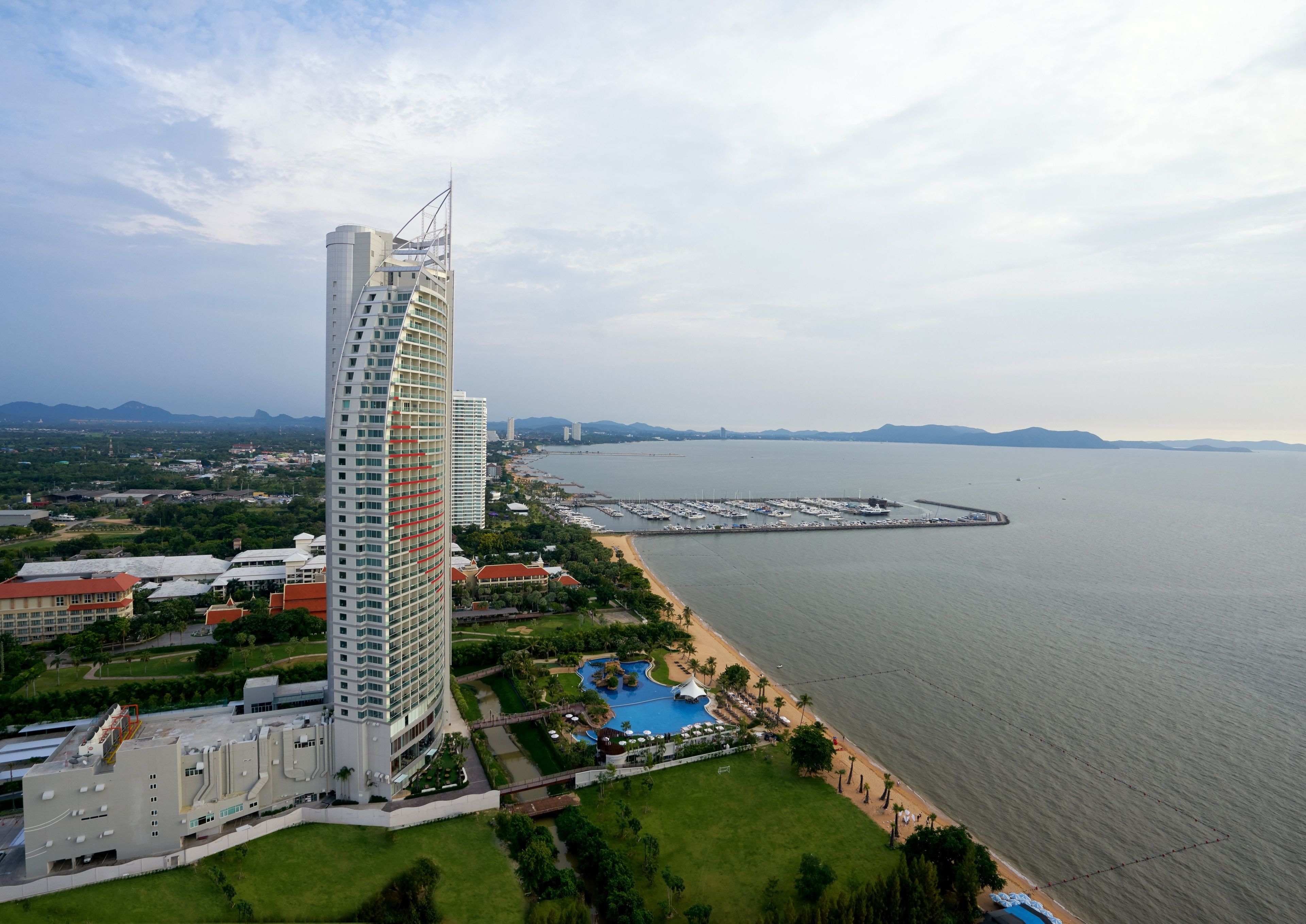 A high-rise hotel with a modern design, a marina, and a beach.