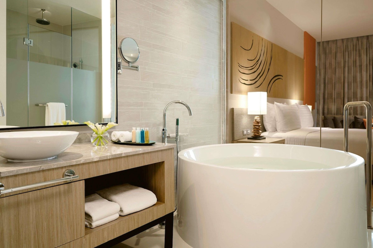 A modern bathroom with a large freestanding bathtub, a glass-enclosed shower, and a vanity with a mirror and toiletries.