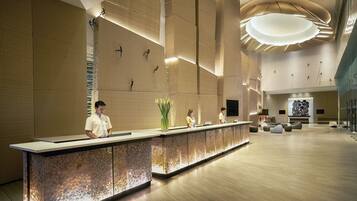 A modern reception area with a stone-textured counter, a large wall with geometric patterns, and a contemporary light fixture.