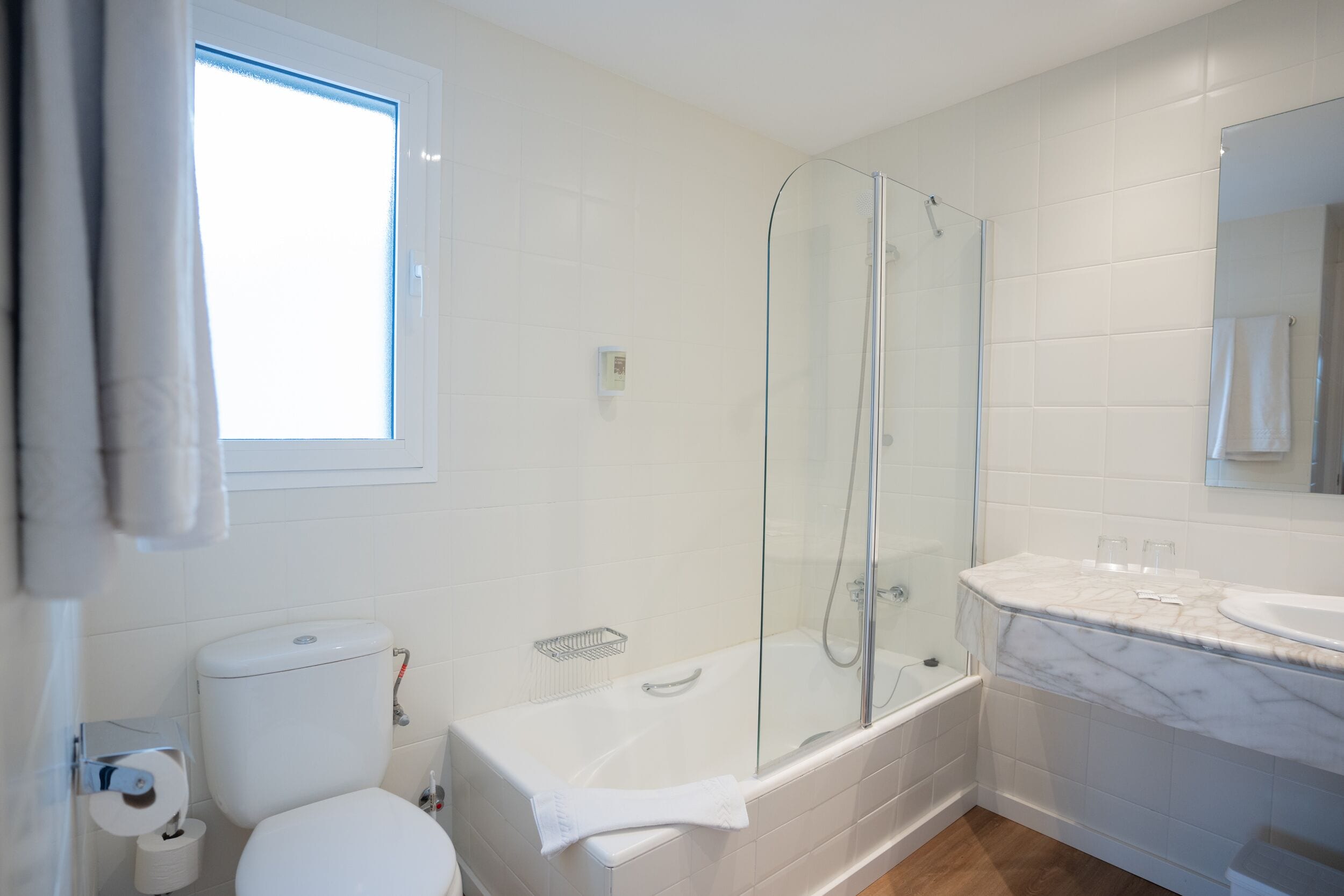 Une salle de bain comprenant des toilettes, un espace douche et un lavabo avec un plan de travail en marbre.