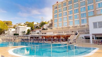 A hotel with a swimming pool, multiple balconies, and a view of surrounding buildings.