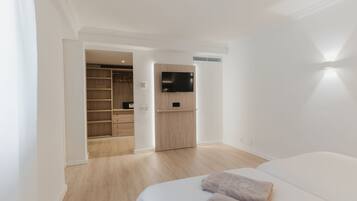 Een moderne slaapkamer met een bed, een aan de muur bevestigde televisie en een inloopkast.