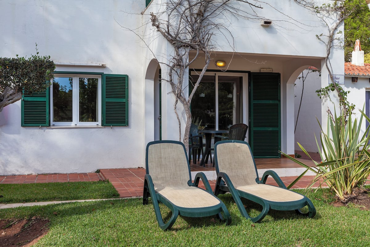 A house with two lounge chairs in the front yard.
