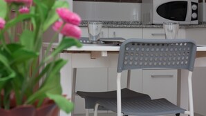 Eine Küche mit einer Mikrowelle, einem Glas und einem Stuhl.