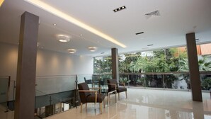 Eine großzügige Lobby mit Glastrennwand, moderner Möblierung und Blick auf Grünflächen.
