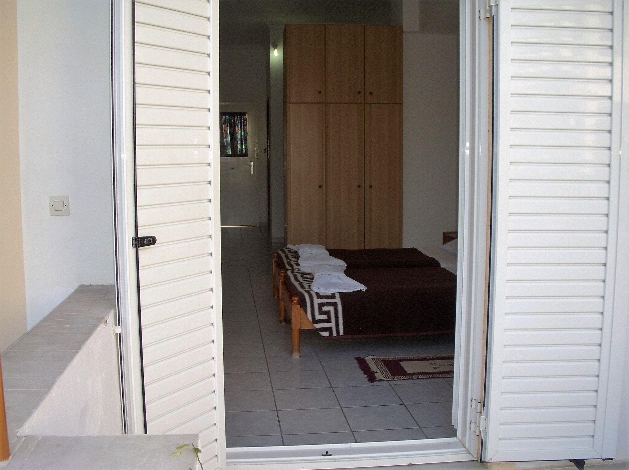 A bedroom with a bed, a wardrobe, and a door leading to another room.