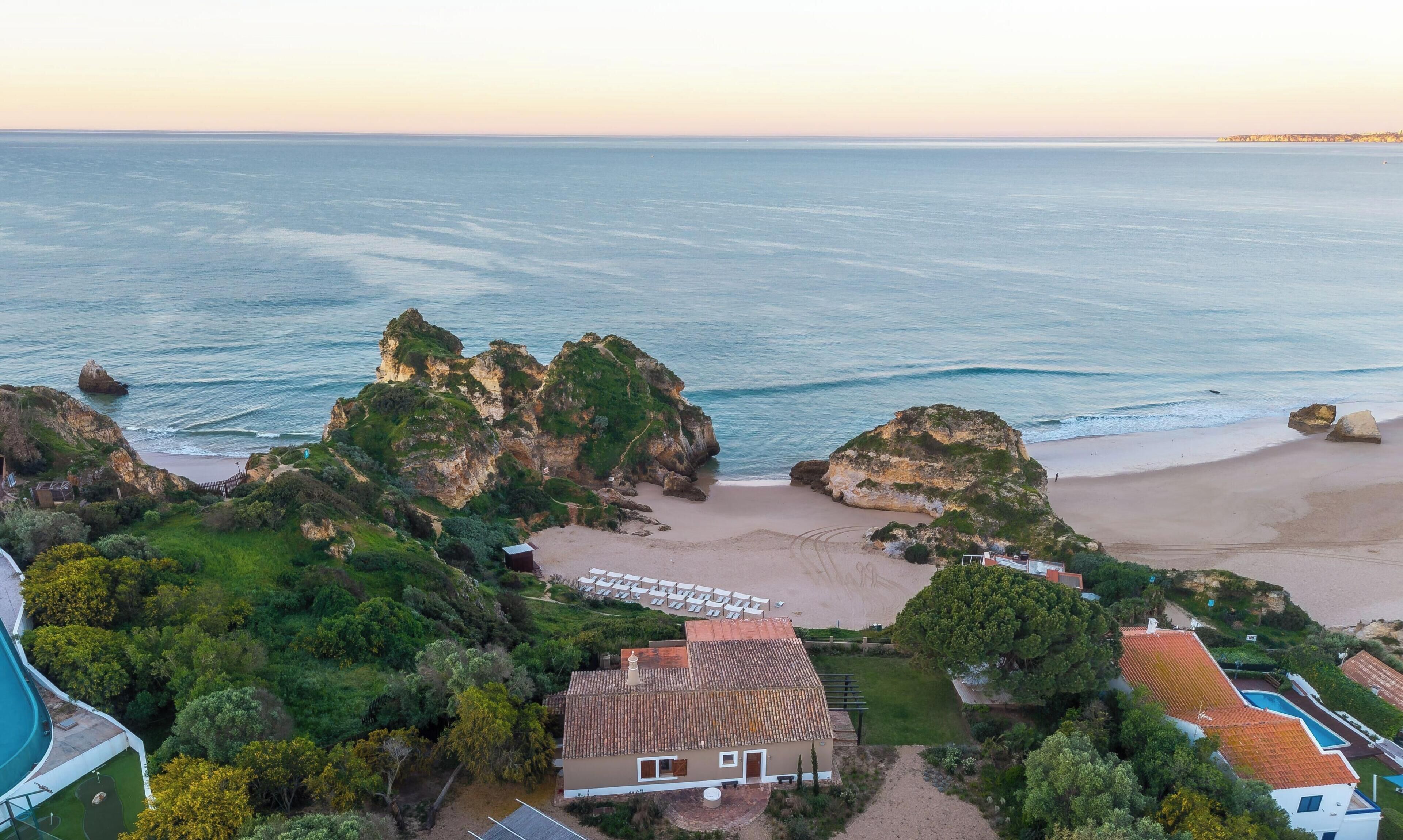 Una propiedad costera con playa, afloramientos rocosos y una piscina.