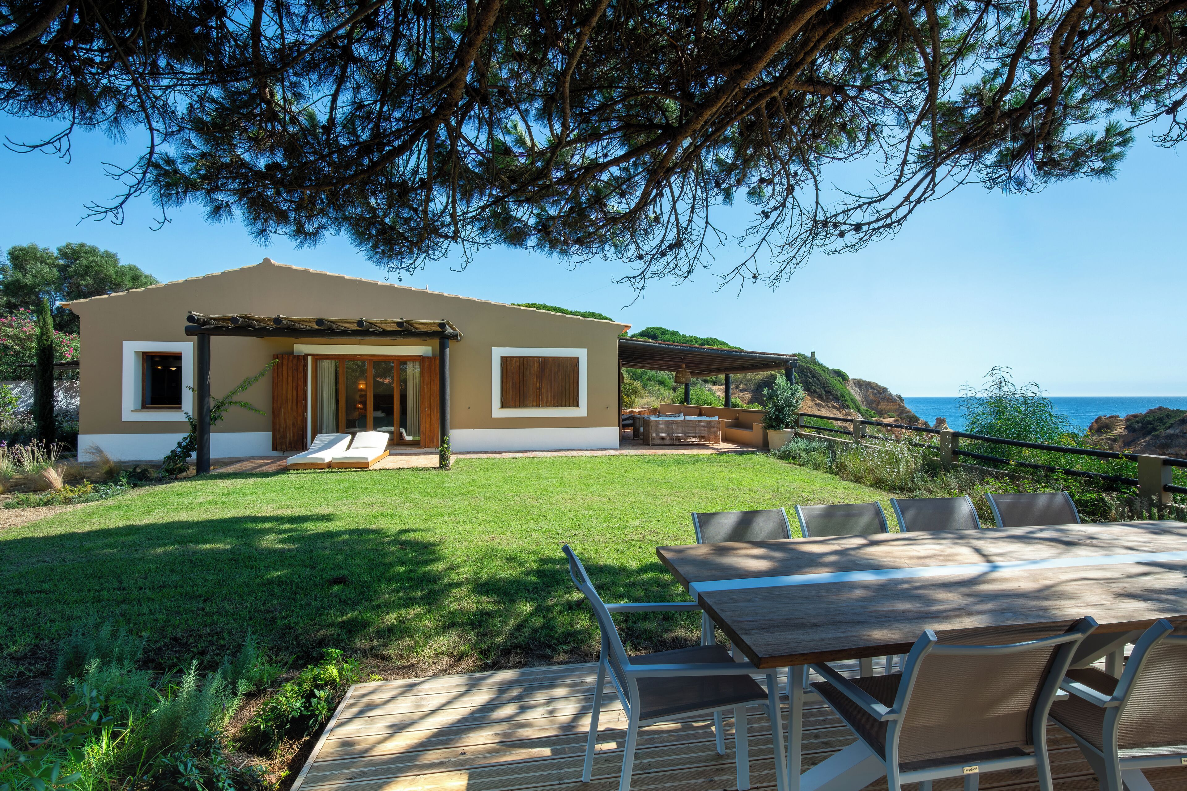 Una casa moderna con patio, un pontile in legno e vista mare.