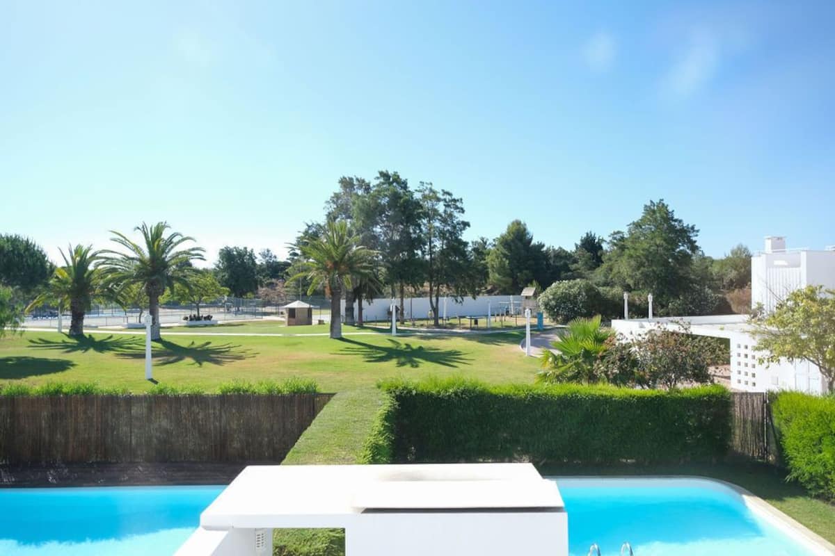 A swimming pool with a white deck, surrounded by well-maintained grass and trees.