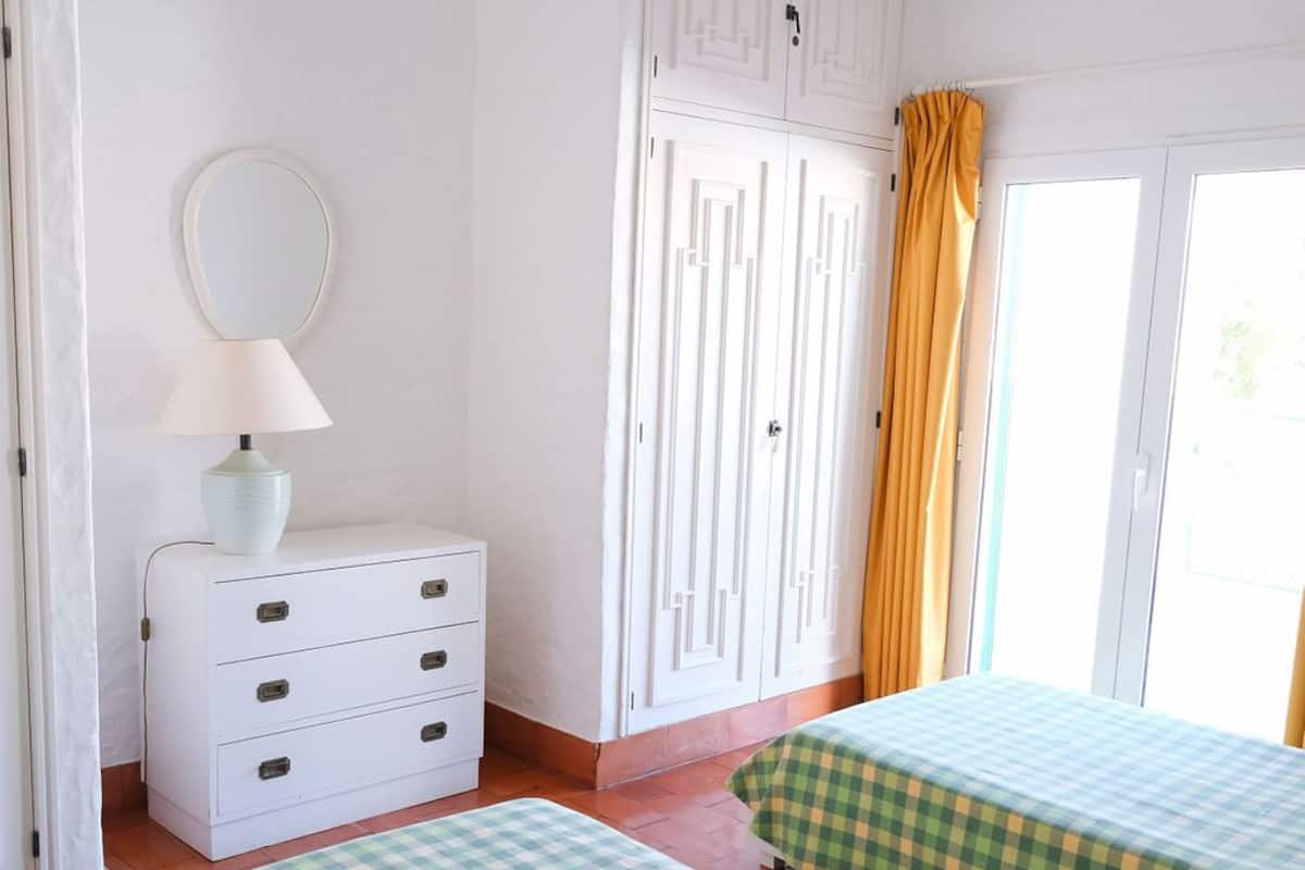 A bedroom with two beds, a dresser, a mirror, and a wardrobe.