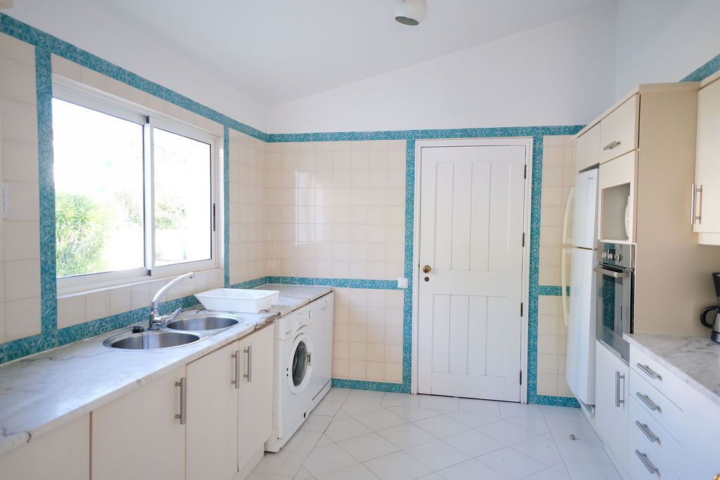 A kitchen with a washing machine, two sinks, a refrigerator, and cabinets.