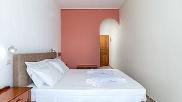 Ein Hotelzimmer mit einem Bett, einem Nachttisch, einer Wandlampe und einer Holztür.