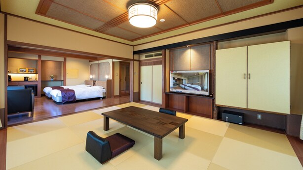 A hotel room with a large bed, a dining table, a small kitchen area, and a wardrobe. - Fujisan Isawa Onsen Hotel Sekitei (Fuefuki)