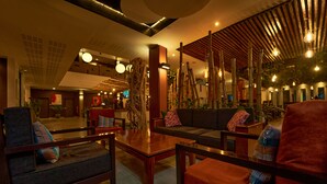A modern lobby with seating areas, a TV, and decorative plants. - Onomo Hotel Lome (Lomé)