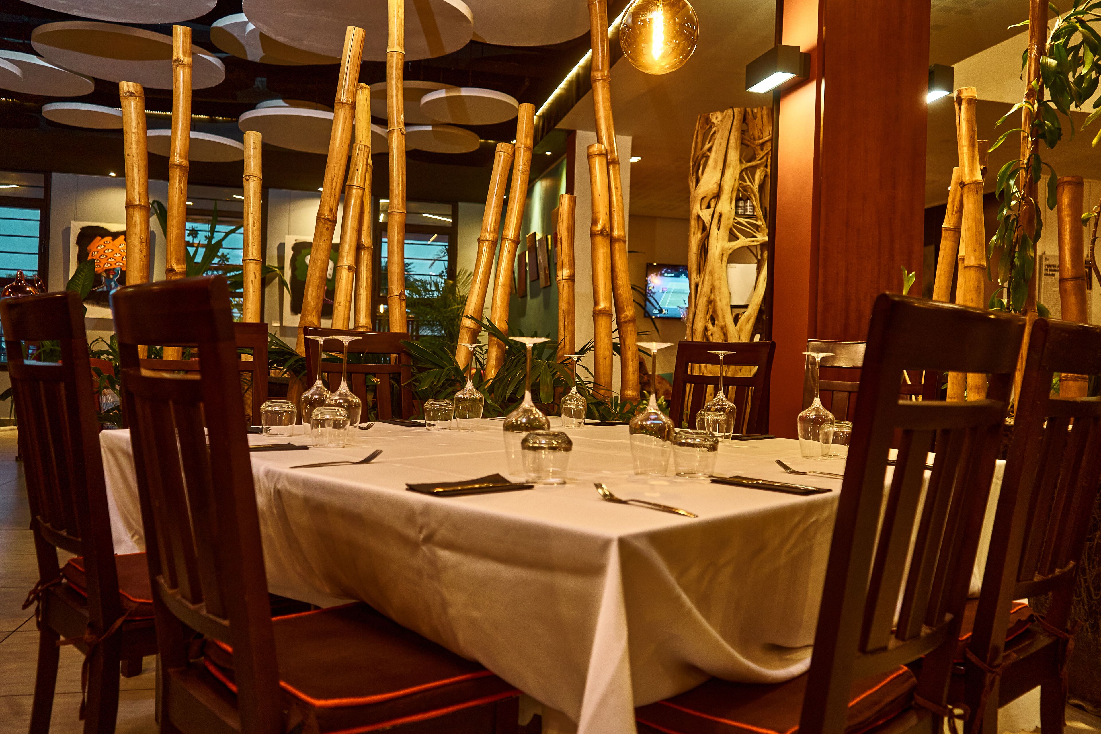 A restaurant with a white tablecloth, wooden chairs, and bamboo decorations.