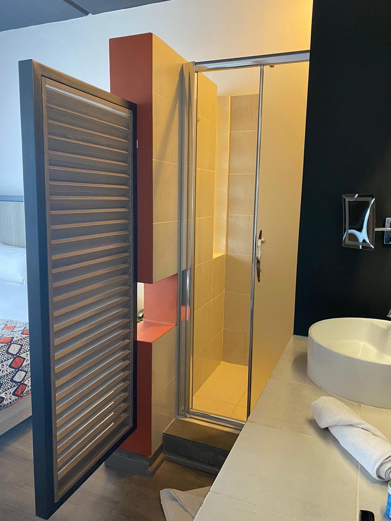 A modern bathroom with a glass shower enclosure, a white sink, and a towel on the counter.