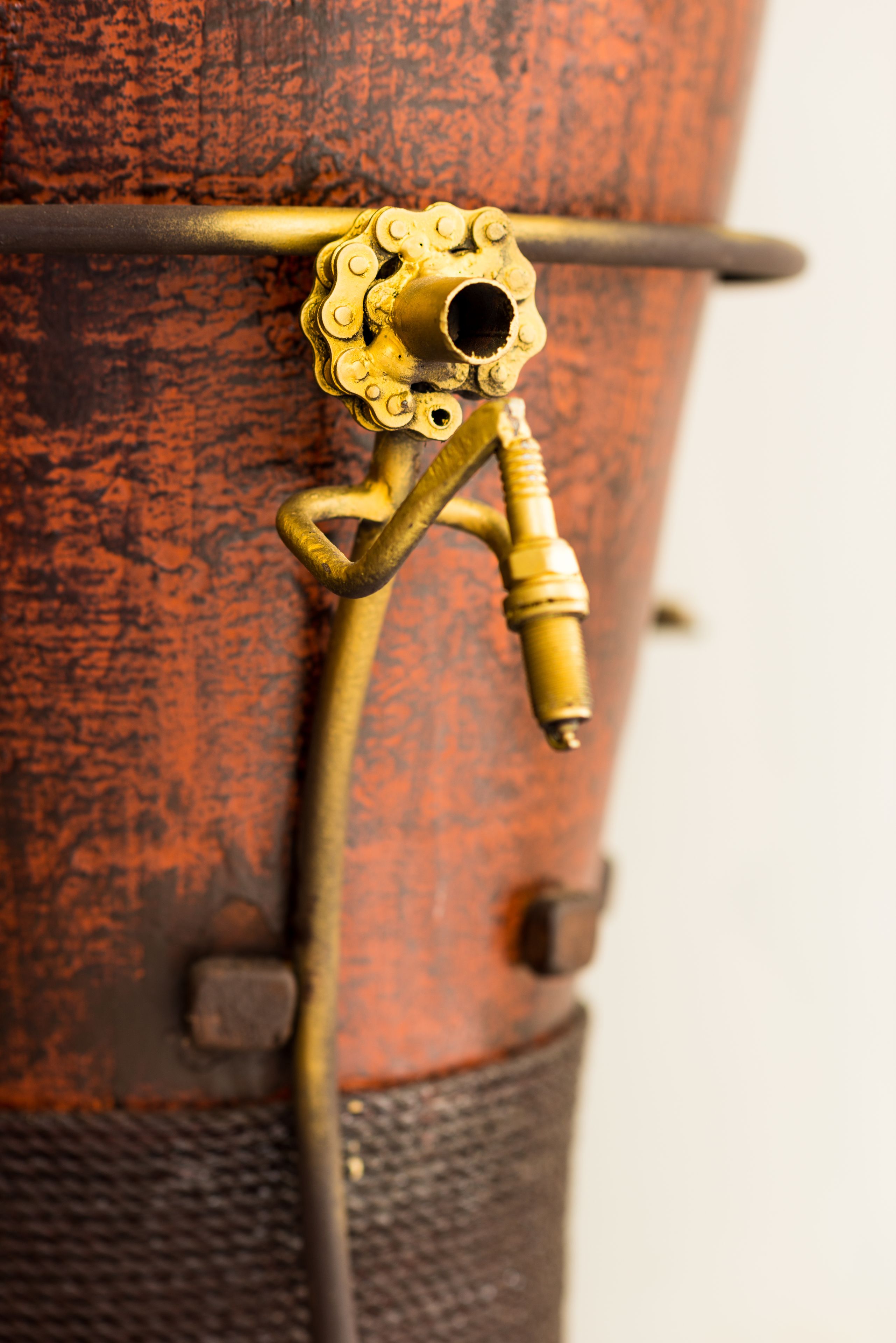 A close-up of a brass valve with a decorative handle on a rusted metal surface.