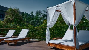 A wooden deck with two lounge chairs and a canopy bed. - Onomo Hotel Lome (Lomé)