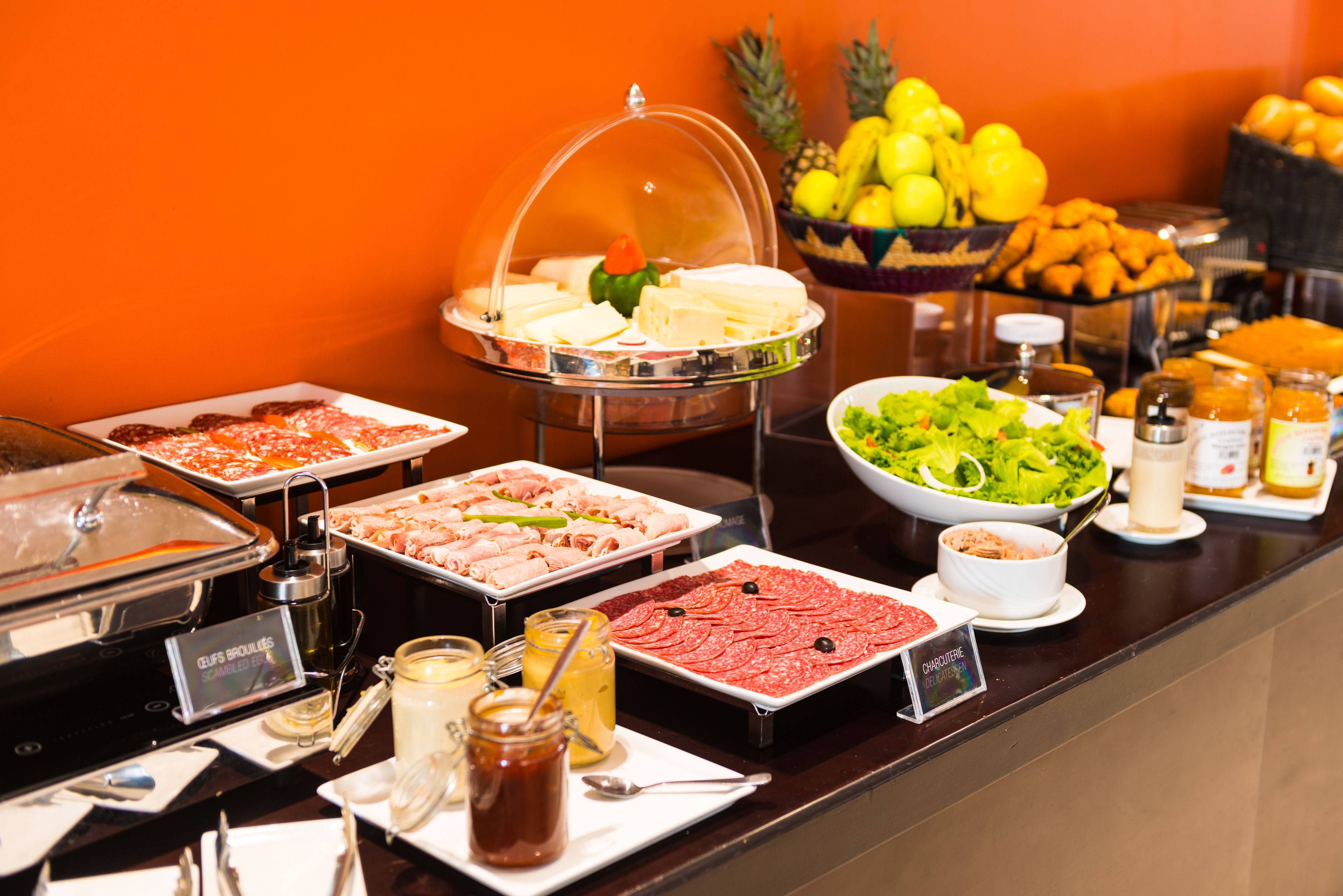 Un buffet proposant une variété de plats, notamment des viandes, des fromages et des salades.