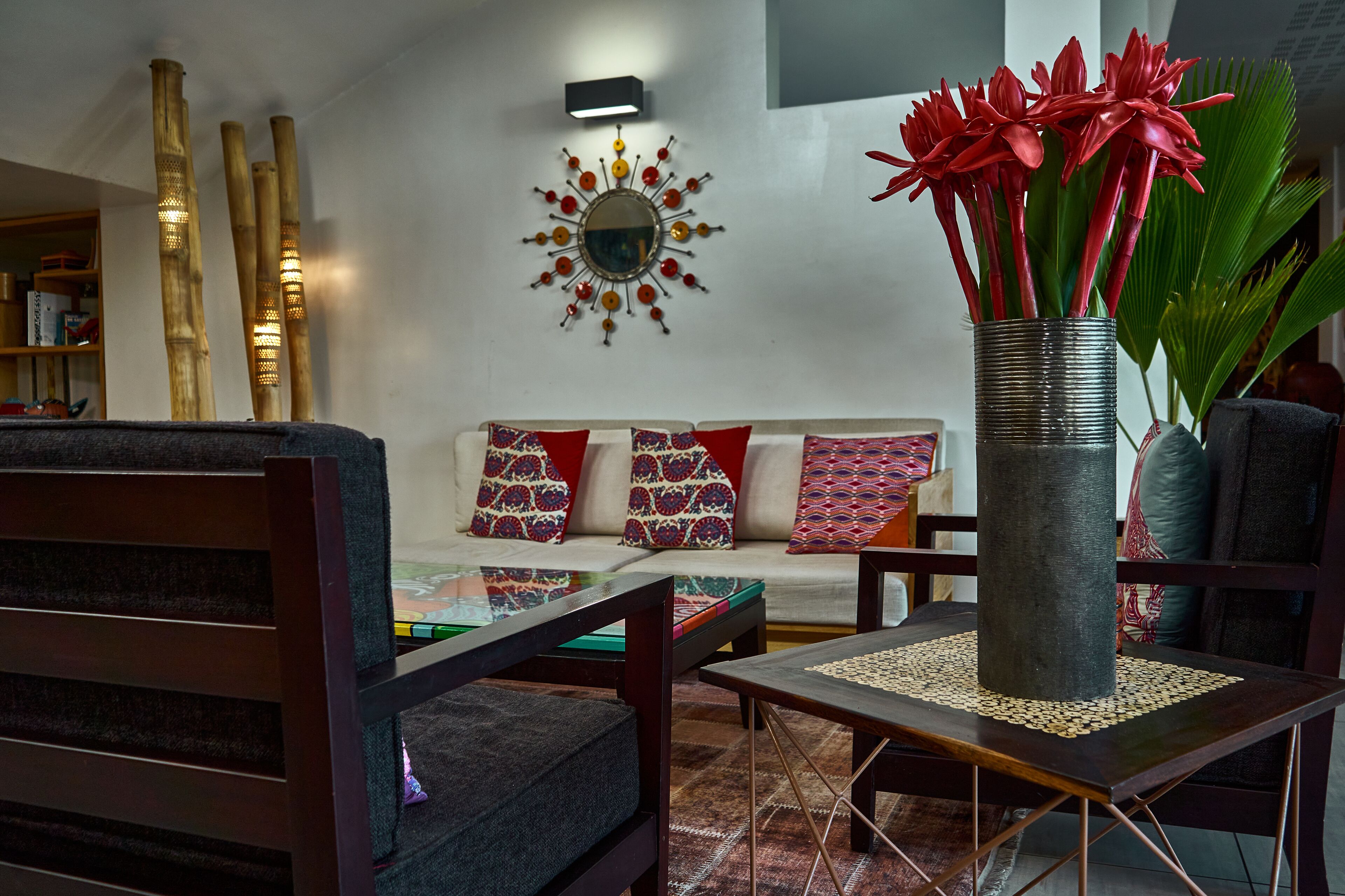 A modern living room with a sofa, coffee table, and a decorative vase with red flowers.