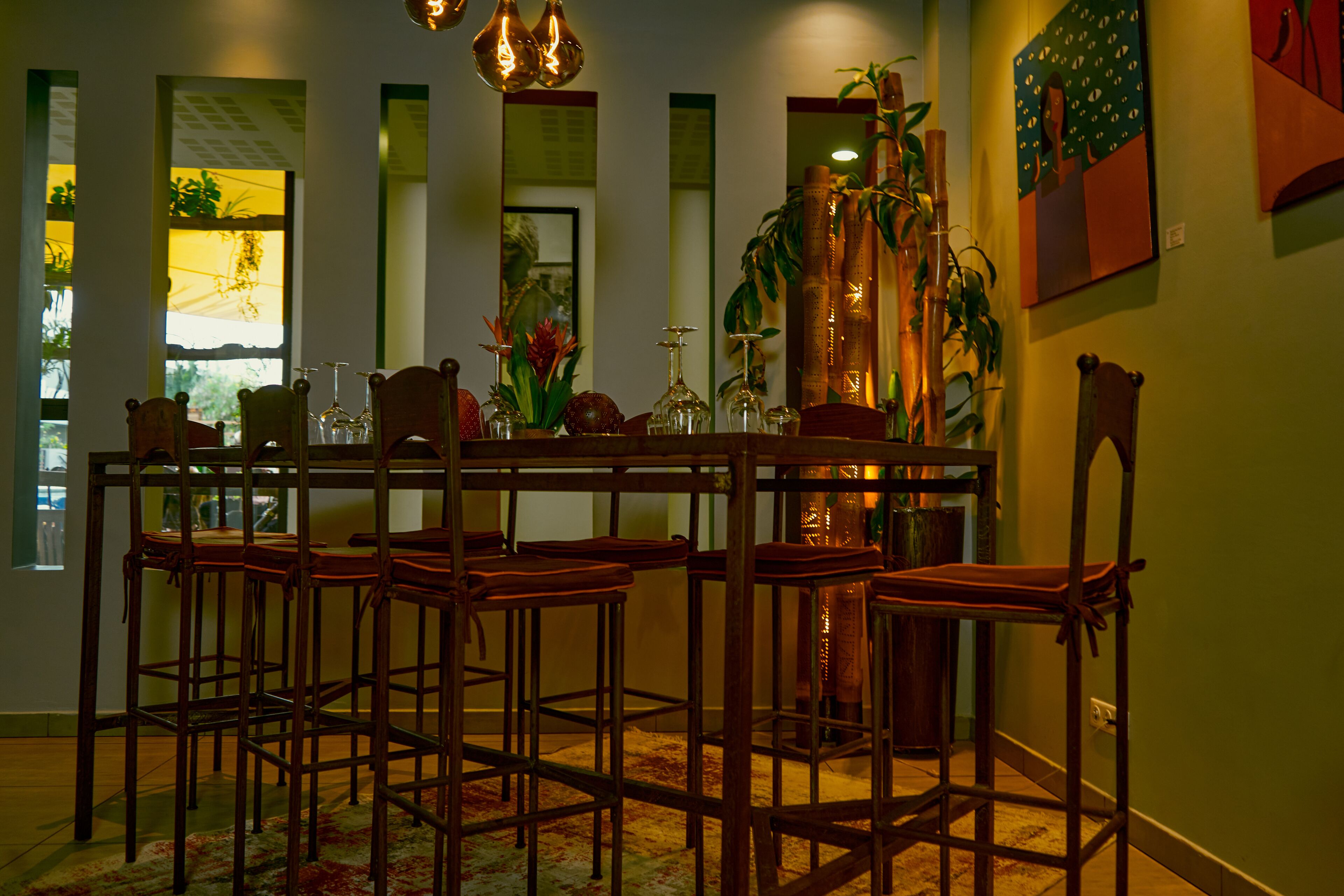 A dining area with a wooden table and chairs, a vase with flowers, and a mirror on the wall.