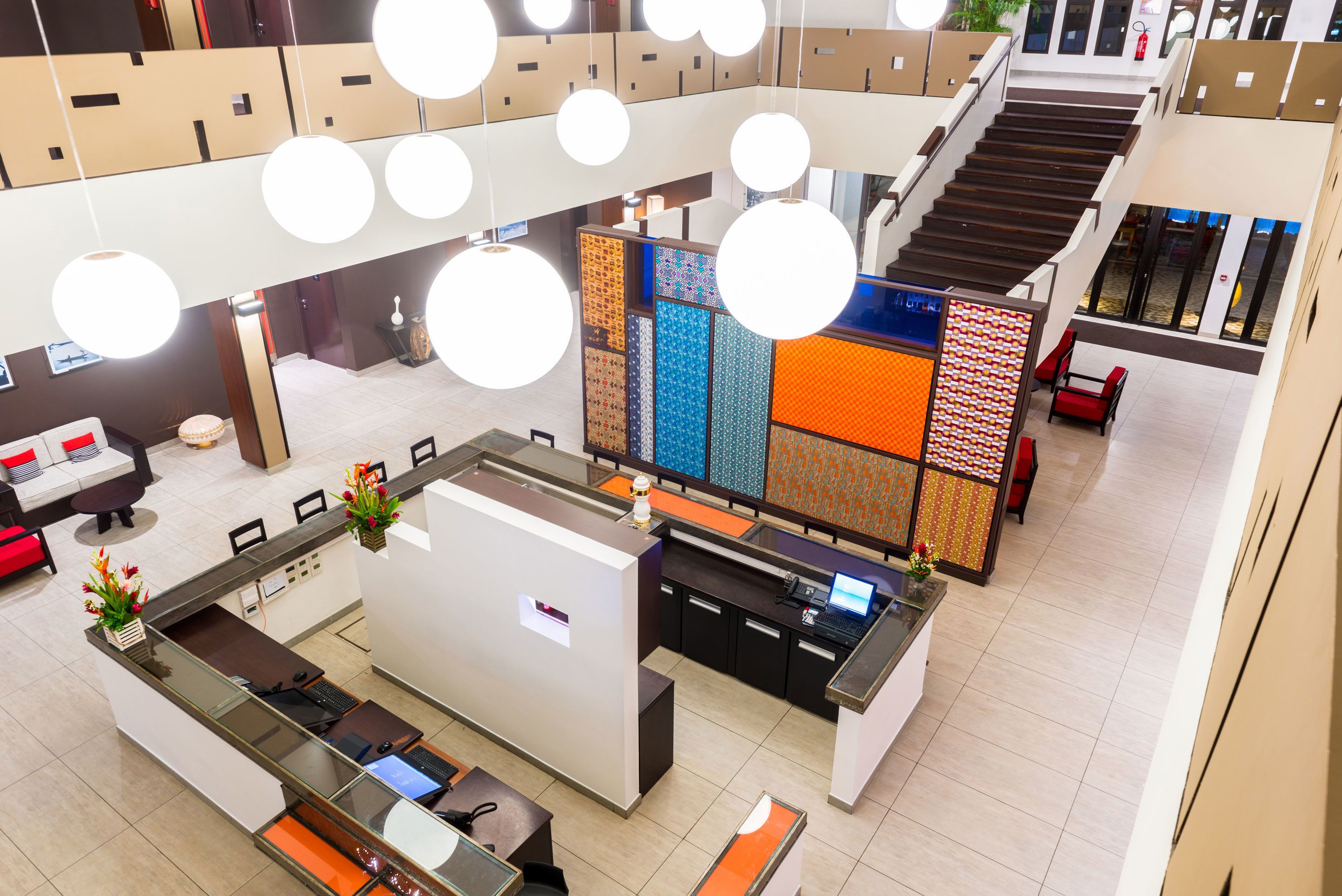 A modern hotel lobby with a reception desk, seating areas, and a staircase.