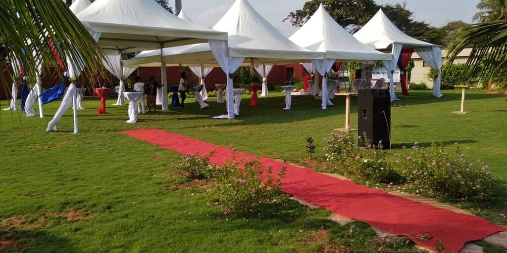A grassy outdoor area with white tents and a red carpet path.