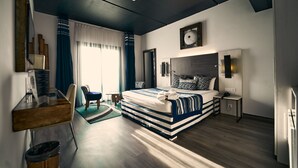 A modern hotel room with a large bed, a desk, a chair, and a small table. - Onomo Hotel Lome (Lomé)