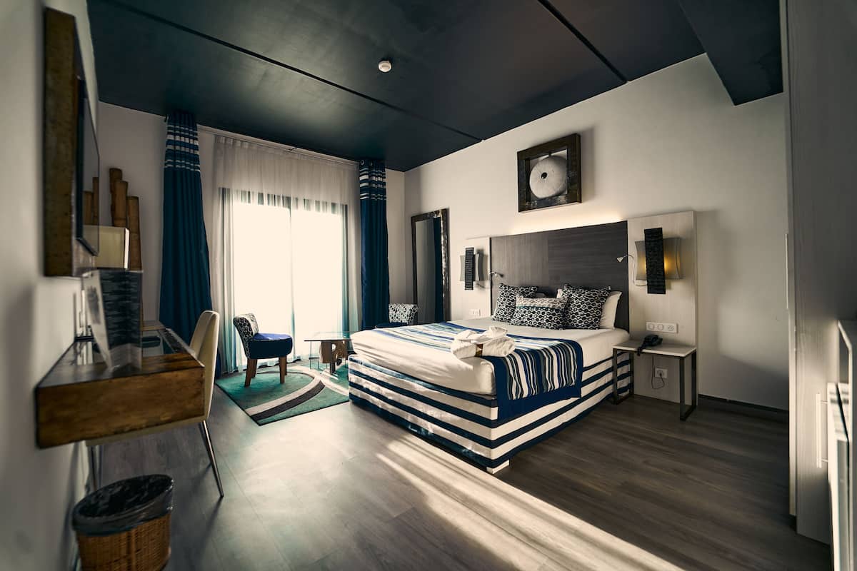 Une chambre d’hôtel moderne équipée d’un grand lit, d’un bureau, d’une chaise et d’une petite table.